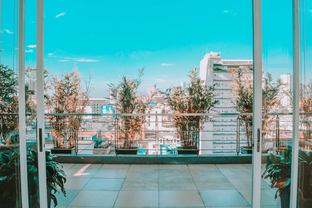 Open laptop on a table on a balcony surrounded by plants