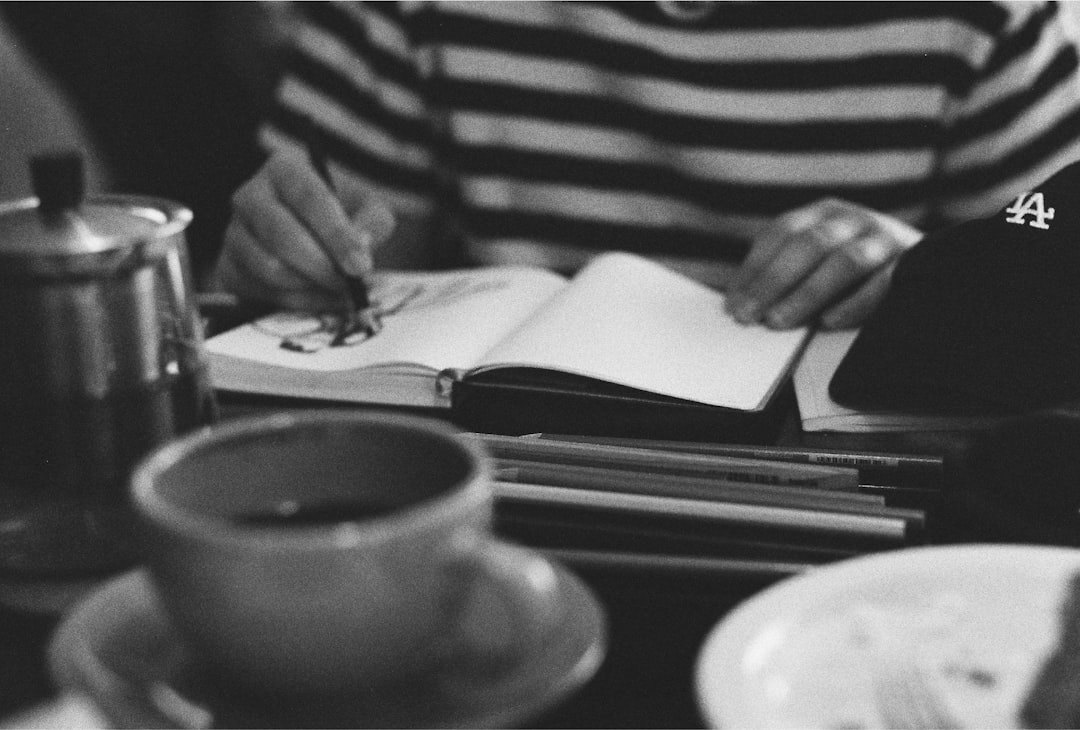 Hand writing in a notebook next to a cup of coffee